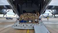Ein A400M mit offeneder Ladeklappe am Boden: Ein Palette mit Gepäck befindet sich darauf.