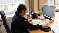 Eine Soldatin sitzt hinter einem Schreibtisch und schaut auf einem Computerbildschirm