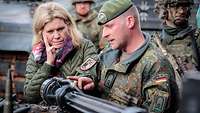 Ein Soldat und eine Zivilistin unterhalten sich. Er erläutert den Aufbau eines Panzerrohres.