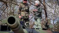 Ein Soldat und eine Zivilistin stehen auf einem Panzer und sprechen miteinander.