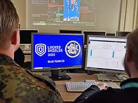 Locked Shields 2023 Zwei Männer sitzen vor zwei Monitoren mit der Inschrift Locked Shields 2023 Blue Team 03.
