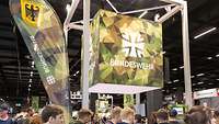 Bundeswehr-Messestand auf der FIBO In einer Halle ein Gerüst mit Kubus und Bundeswehr-Schriftzug. Davor die Köpfe vieler Besuchender.