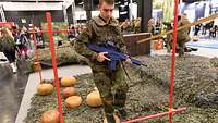 Junger Mann mit Uniform und Übungswaffe balanciert über verschieden große Medizinbälle.