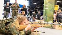 Frau mit Laser-Pointer-Gewehr im Anschlag. Sie blickt konzentriert in die Visiereinrichtung.