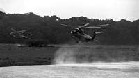 Zwei CH-53-Hubschrauber fliegen im Tiefflug über eine Gewässer.