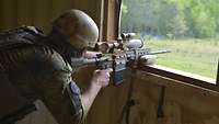 Ein deutscher Soldat schießt mit einem Gewehr G28, die Waffe ruht auf einer Fensterbank.