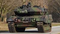 Ein Kampfpanzer Leopard 2A7 in Frontalansicht auf einer Straße. Im Hintergrund Wald.
