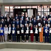 Eine große Gruppe Menschen steht in einem Atrium auf einer Treppe.