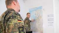 A soldier showing something on a map to another soldier.
