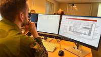 Ein Soldat sitzt in einem Computerhörsaal vor zwei Monitoren.
