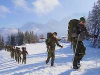 Eine Gruppe von Soldaten läuft in einer Linie mit Schneeschuhen und Skistöcken.