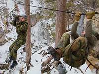 Zwei Männer mit Klettergurt und Helm hängen an einem Seil. 