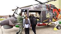 Mädchen sitzen in einem Hubschrauber und unterhalten sich mit Soldaten.