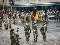 Drei deutsche Soldaten marschieren mit der deutschen Truppenfahne auf einem Platz in Tallinn