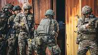 Deutsche und britische Soldaten stürmen gemeinsam einen Kontainer durch eine Türe