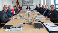 Frauen und Männer sitzen an einem Konferenztisch