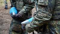 Kein Leichtgewicht Zwei Soldaten tragen blaue Artilleriegeschosse.