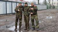 Zwei Soldaten und eine Soldatin stehen dicht nebeneinander und posieren für ein Bild.