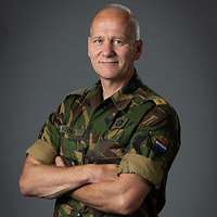 Ein niederländischer General verschränkt die Arme und schaut freundlich in die Kamera.