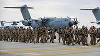 Eine Kolonne von Soldaten läuft auf einem Rollfeld an mehreren Transportflugzeugen A400M vorbei