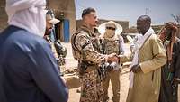 Ein Soldat schüttelt die Hand eines Bewohners in Mali, ein Soldat und drei Bewohner stehen daneben