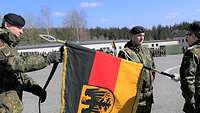 Soldat befästigt ein Band an der Flagge.