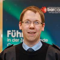 Hauptmann Kai K. blickt in die Kamera, hinter ihm ist ein Plakat des „BarCamps“ zu sehen