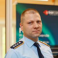 Hauptmann Rico S. blickt in die Kamera, hinter ihm ist ein Plakat des „BarCamps“ zu sehen