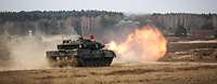 Ein Kampfpanzer Leopard schießt auf dem Truppenübungsplatz. Ein Feuerball kommt aus der Kanone.