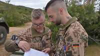 Zwei Soldaten besprechen etwas, einer hält einen geöffneten Ordner mit Papier.