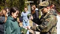 Girls Day Soldat zeigt das Kochgeschirr.