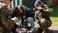 Mädchen des GirlsDay und Soldaten essen mit Kochgeschirr.
