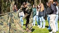 Soldat baut vor eine Meute Mädels ein Zelt auf.