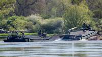 Zwei Amphibienfahrzeuge fahren vom Ufer aus in einen Fluss.