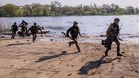 Soldaten verlassen am Ufer Schlauchboote und stürmen an Land.