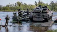 Ein Kampfpanzer fährt von einer Fähre herunter.