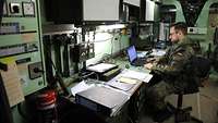 Szene in einem Bürocontainer. Soldat arbeitet am Laptop