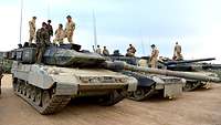 Auf mehreren Panzern nebeneinander stehen jeweils deutsche und norwegische Soldaten.