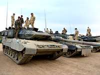 Auf mehreren Panzern nebeneinander stehen jeweils deutsche und norwegische Soldaten.