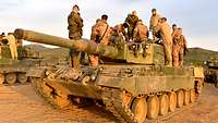 Auf einem norwegischen Panzer stehen mehrere deutsche und norwegische Soldaten.
