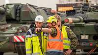Drei Soldaten im Gespräch von Fahrzeugen der Bundeswehr.