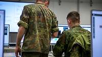 Flecktarnuniformen ohne Hoheitsabzeichen Deutsche und Ukrainische Soldaten nebeneinander an einem Computer.