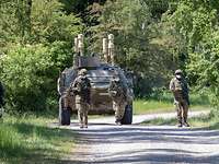 Soldaten laufen vpr einem Transportpanzer.