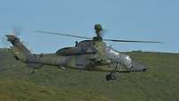 Ein Hubschrauber fliegt vor einem Berg.