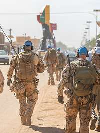 Mehrere Soldaten mit blauen Basecaps laufen auf einer Straße in Gao.