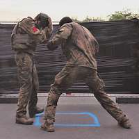 Zwei Soldaten in Flecktarn mit Kopfschutz boxen vor einer schwarzen Stellwand.