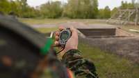 Blick über die Schulter: Ein Soldat hält eine Stoppuhr in der Hand.