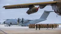Mehrere Soldaten stehen vor einem Transportflugzeug A400M auf einem Rollfeld