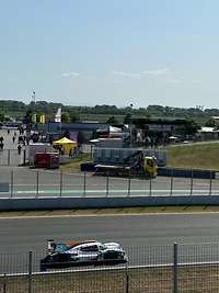 Ein Rennauto fährt in der Motorsport Arena, im Hintergrund der Karrieretruck der Bundeswehr.