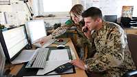Two cooperating soldiers at a computer.